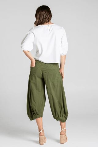 Woman wearing a white puff sleeve blouse and olive green cropped harem pants.
