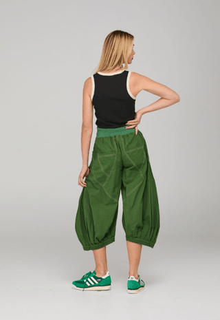 Woman wearing a black tank top and green balloon pants with green sneakers