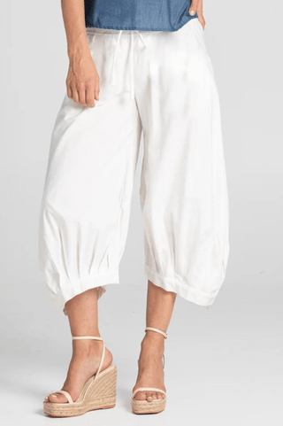 Woman wearing white linen wide leg cropped culotte pants and beige wedge sandals.
