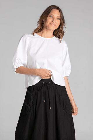 Woman wearing a white puff sleeve blouse and black drawstring maxi skirt.