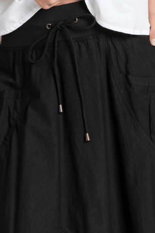 Black high-waisted leisure pants with a drawstring waist and metal tipped cords.