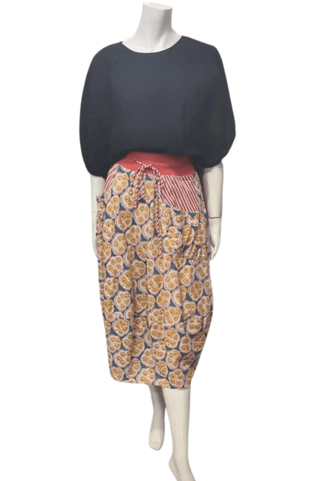 Woman mannequin wearing a black top and patterned midi skirt with red waistband.