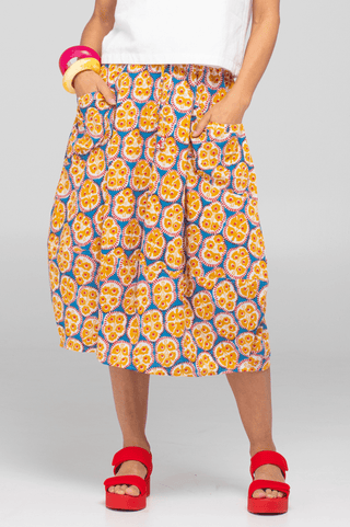 Woman wearing a colorful patterned midi skirt with pockets and red platform sandals.