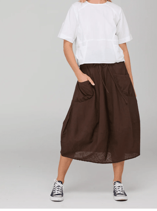 Woman wearing a white t-shirt and a brown midi skirt with pockets and sneakers