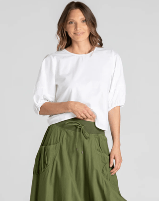 Woman wearing a white puff sleeve top and an olive green drawstring midi skirt.