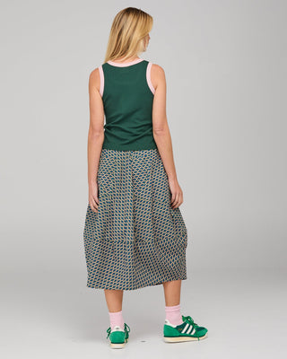 Woman wearing a green tank top, printed midi skirt, and green Adidas sneakers from behind.
