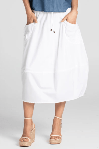 Woman wearing a white midi skirt with pockets and beige wedge sandals.