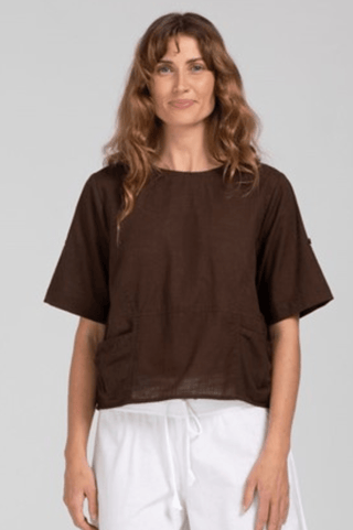 Woman wearing a dark brown linen short sleeve blouse and white drawstring pants.