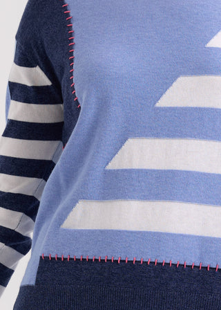 Close-up of a blue and white striped knit sweatshirt with pink contrast stitching.