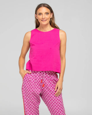 Woman wearing a bright pink sleeveless linen top and patterned pink and white lounge pants.