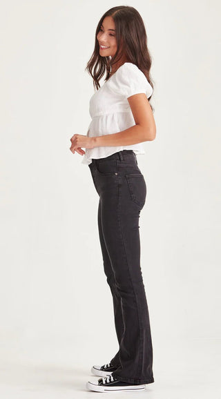 Woman wearing a white puff sleeve blouse and black flared denim jeans.