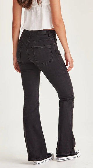 Woman wearing black flared denim jeans and white crop top.
