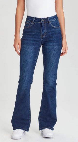 Woman wearing high-waisted blue flare denim jeans and white sneakers.