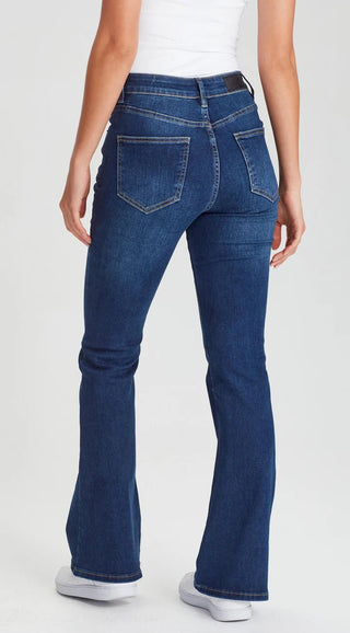 Woman wearing dark wash blue flare denim jeans and white sneakers.