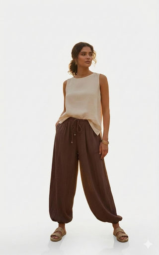 Woman wearing a beige sleeveless linen top and brown wide-leg lounge pants.