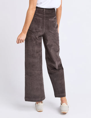 Woman wearing brown wide-leg corduroy pants and white sneakers.