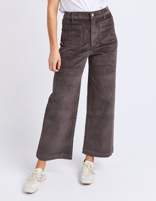 Woman wearing charcoal grey corduroy wide leg cropped pants and white sneakers.