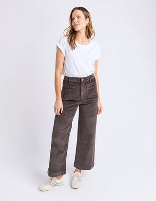 Woman wearing a white t-shirt and brown wide-leg corduroy pants with white sneakers.