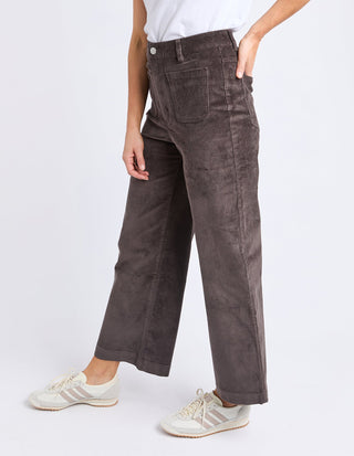 Woman wearing brown corduroy wide-leg pants and white sneakers.