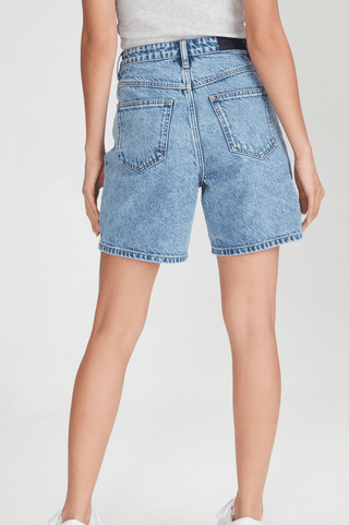 Woman wearing blue denim shorts and a grey ribbed top, back view.