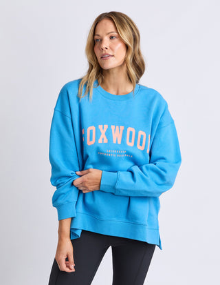 Woman wearing a blue Foxwood leisurewear sweatshirt and black leggings.