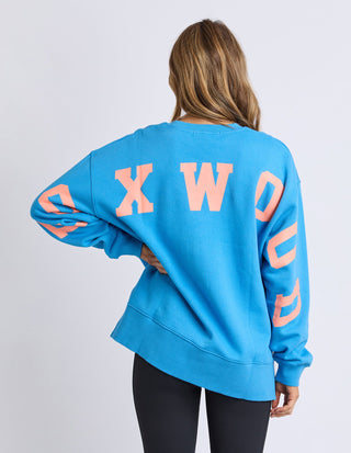Woman wearing a blue Foxwood sweatshirt with large pink lettering on the back.