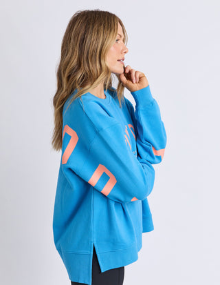 Woman wearing a blue long sleeve sweatshirt with coral graphic print