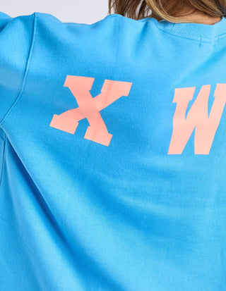 Back view of a bright blue sweatshirt featuring large pink graphic lettering.