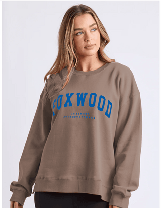 Woman wearing a brown Foxwood leisurewear sweatshirt with blue graphic lettering.