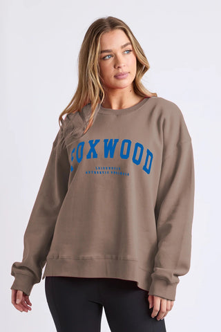 Woman wearing a brown Foxwood graphic sweatshirt and black leggings.