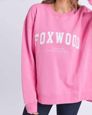 Woman wearing a pink Foxwood leisurefit sweatshirt with white graphic lettering.