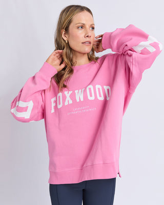 Woman wearing a pink Foxwood leisurefit sweatshirt with white graphic text.