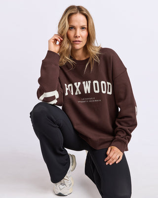 Woman wearing a brown Foxwood leisurefit sweatshirt and black lounge pants.