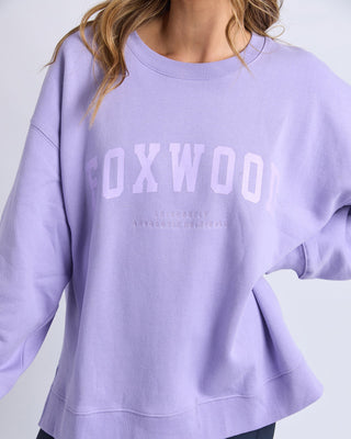 Woman wearing a lilac Foxwood sweatshirt with embossed lettering.