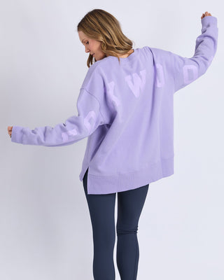 Woman wearing a lilac oversized sweatshirt with Foxwood lettering and navy leggings