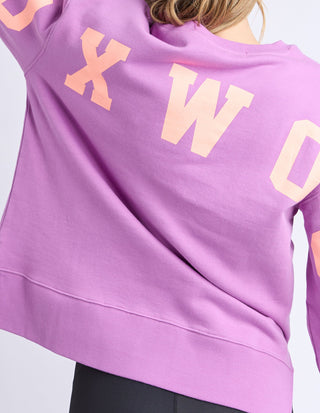 Close-up of a purple Foxwood sweatshirt with peach-colored lettering on the back