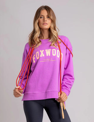 Woman wearing a purple Foxwood sweatshirt and black leggings holding red jump ropes.