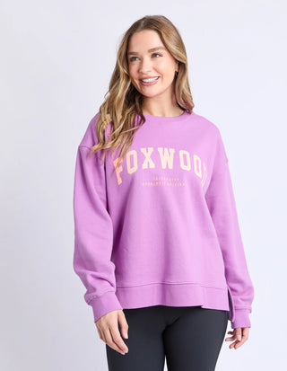 Woman wearing a purple Foxwood sweatshirt and black leggings.