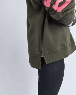 Olive green oversized sweatshirt with pink graphic detail and side slit hem.