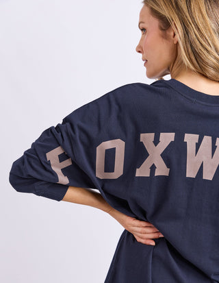 Woman wearing a navy Foxwood graphic sweatshirt with large lettering on the back.