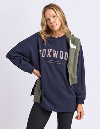 Woman wearing a navy Foxwood oversized sweatshirt and black leggings.