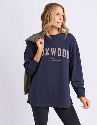 Woman wearing a navy Foxwood oversized long sleeve sweatshirt and black leggings.
