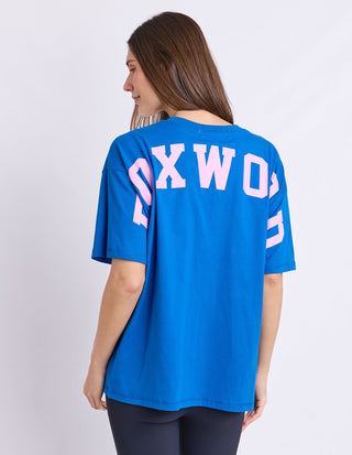 Detail of neon pink Foxwood logo on cobalt blue cotton tee
