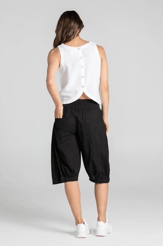 Woman wearing a white sleeveless linen top and black cropped wide-leg pants.