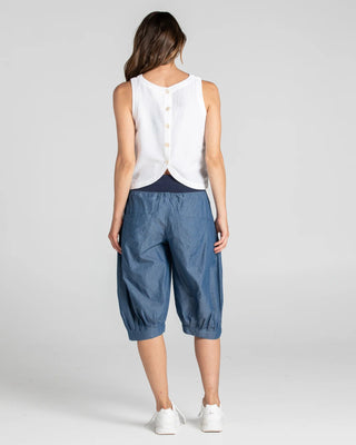 Woman wearing a white linen sleeveless top and blue cropped wide-leg lounge pants.