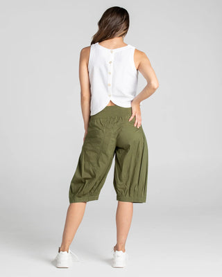 Woman from behind wearing a white button-back sleeveless top and olive green culotte pants.