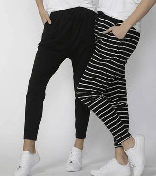 Woman wearing black joggers and striped leisure pants with white sneakers.