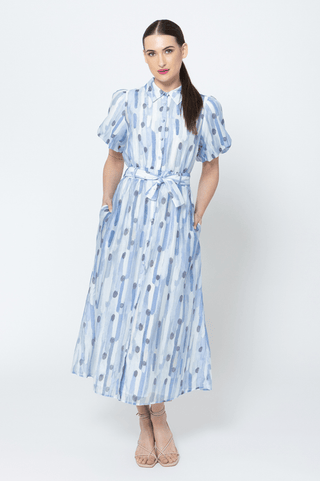 Woman wearing a blue and white abstract print midi dress with a tie waist and short sleeves.