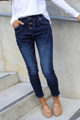 Woman wearing dark wash denim skinny jeans with button fly and beige loafers.