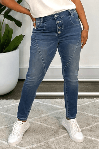 Woman wearing high-waisted blue denim button-fly skinny jeans and white sneakers.